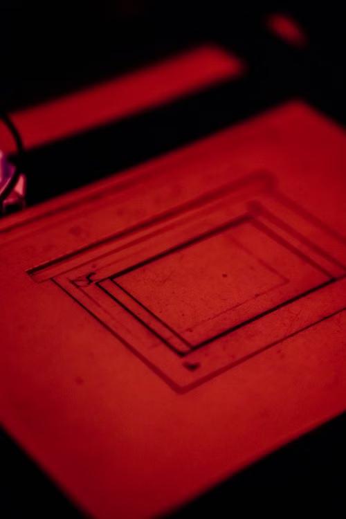 Red-lit photolithography workspace with precision equipment used during semiconductor fabrication.